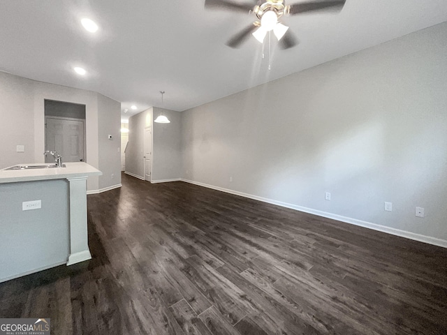 unfurnished living room with ceiling fan, dark hardwood / wood-style floors, and sink