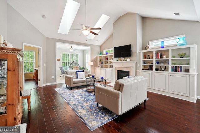 living room featuring dark wood-type flooring, a skylight, high vaulted ceiling, and ceiling fan