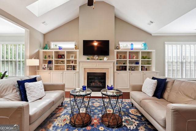 living room with a healthy amount of sunlight, vaulted ceiling with skylight, a high end fireplace, and hardwood / wood-style floors