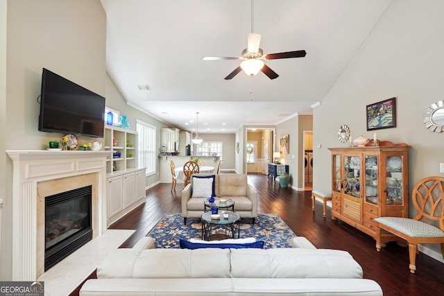 living room featuring dark hardwood / wood-style floors, high vaulted ceiling, ceiling fan, a high end fireplace, and crown molding