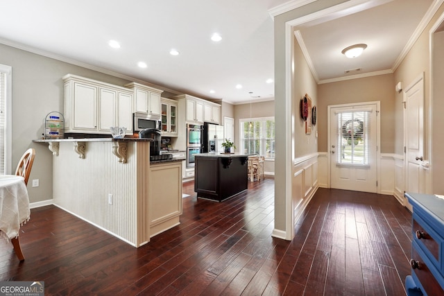 kitchen with a breakfast bar area, crown molding, appliances with stainless steel finishes, dark hardwood / wood-style flooring, and kitchen peninsula