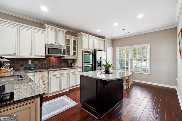 kitchen featuring a kitchen bar, light stone counters, decorative light fixtures, appliances with stainless steel finishes, and a kitchen island