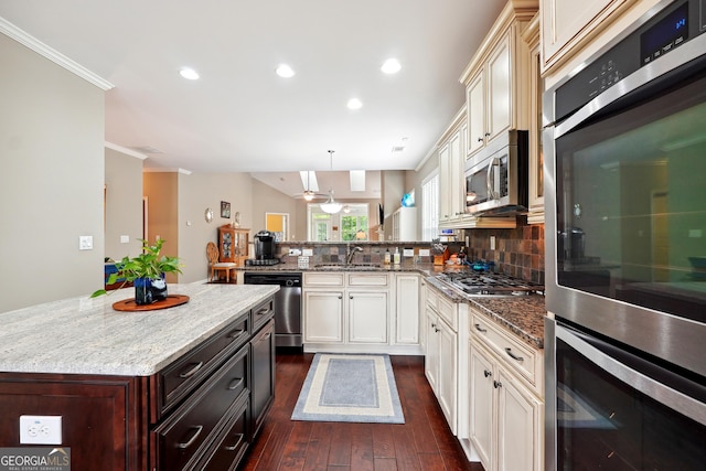 kitchen with appliances with stainless steel finishes, tasteful backsplash, hanging light fixtures, ornamental molding, and kitchen peninsula