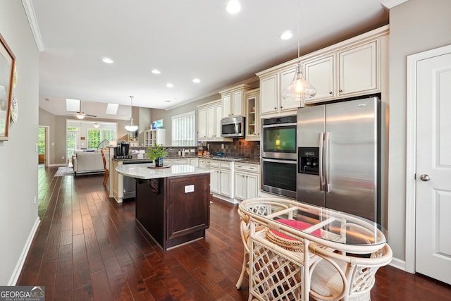 kitchen featuring a breakfast bar area, light stone counters, decorative light fixtures, a kitchen island, and stainless steel appliances