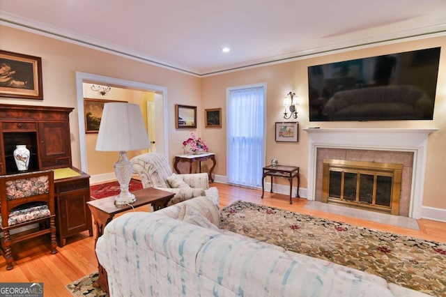 living room featuring light hardwood / wood-style floors, ornamental molding, and a tile fireplace