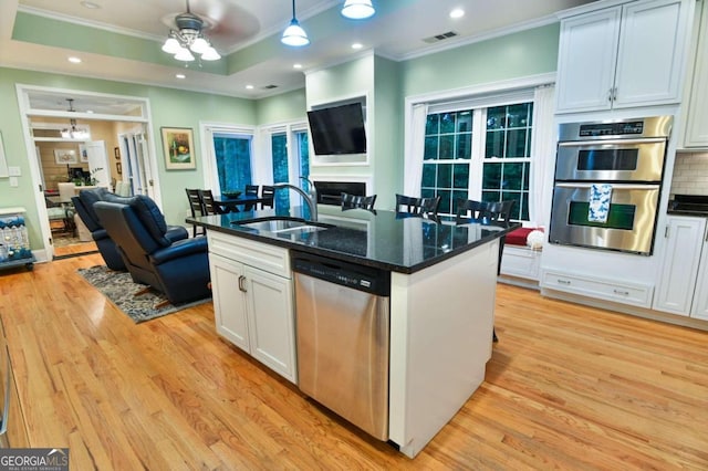 kitchen featuring light wood-type flooring, stainless steel appliances, decorative backsplash, and white cabinetry