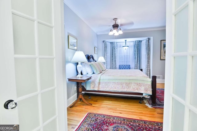 bedroom with hardwood / wood-style floors, crown molding, and ceiling fan