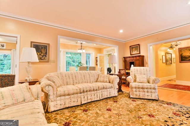 living room with hardwood / wood-style flooring, an inviting chandelier, ornamental molding, and a healthy amount of sunlight