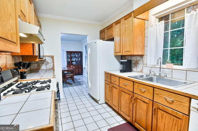 kitchen with tile counters, tasteful backsplash, light tile patterned floors, sink, and white appliances