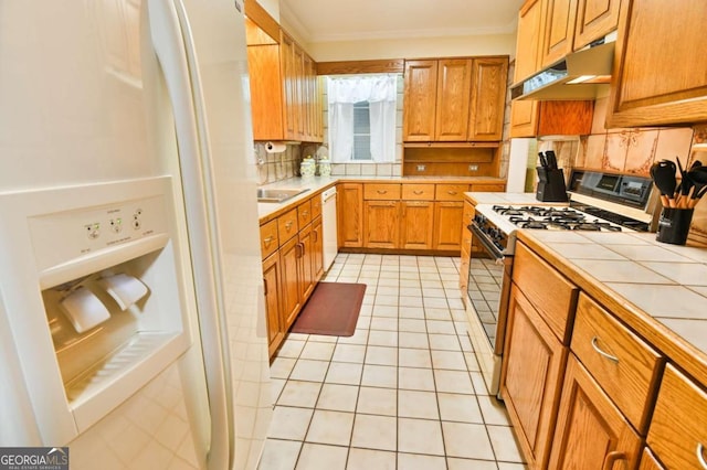 kitchen with wall chimney exhaust hood, tasteful backsplash, gas range, dishwasher, and light tile patterned floors