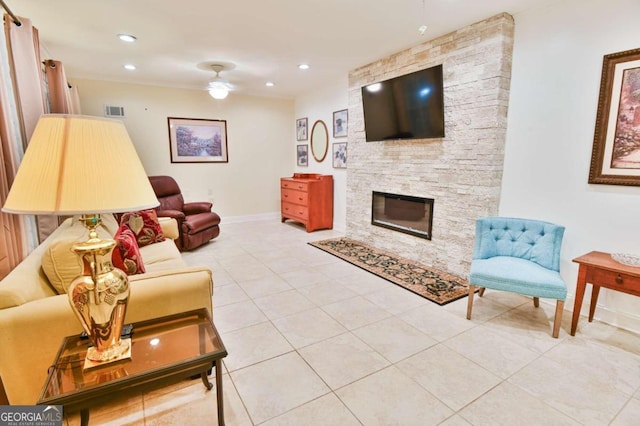 tiled living room featuring ceiling fan and a stone fireplace