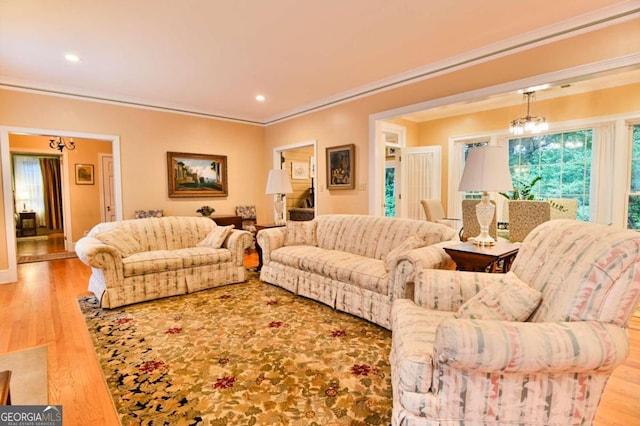 living room with light wood-type flooring, a notable chandelier, and crown molding