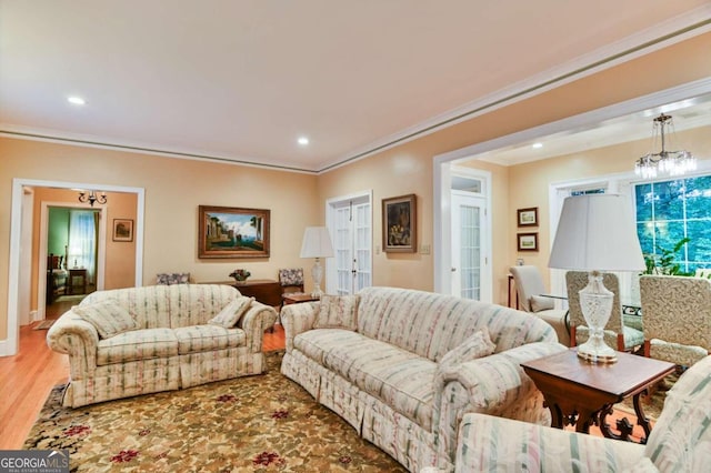 living room with hardwood / wood-style flooring, a chandelier, and ornamental molding