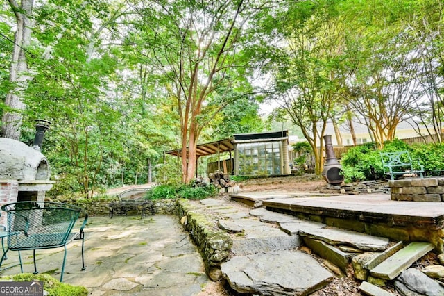 view of patio featuring fence, exterior fireplace, and an outdoor structure