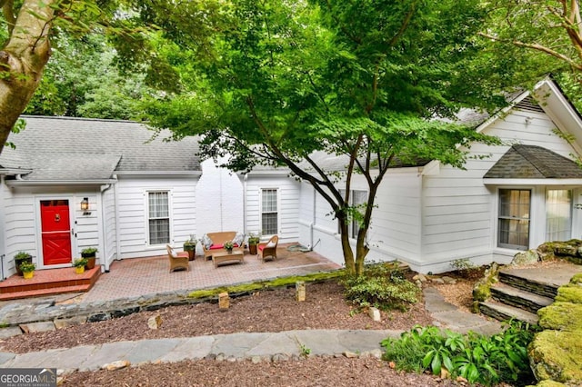 view of front of home with roof with shingles, a patio area, and an outdoor living space