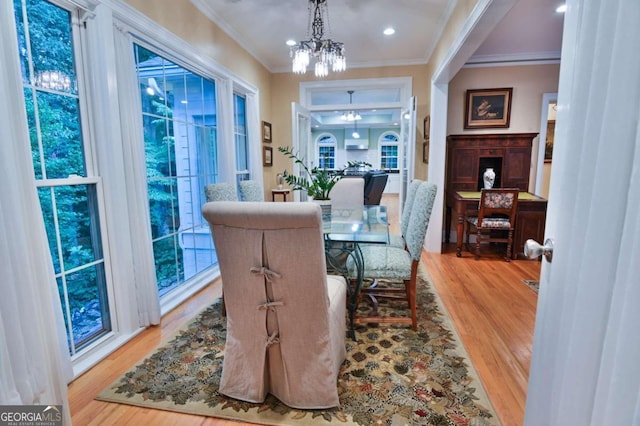 dining space featuring light wood-type flooring, crown molding, and a chandelier