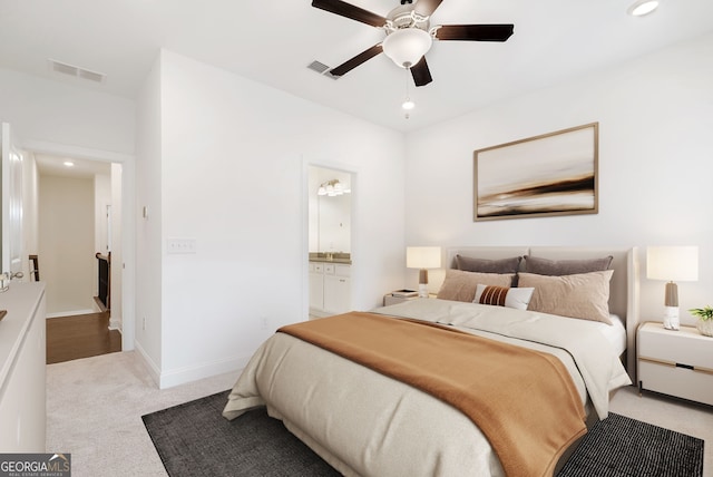 bedroom with ensuite bath, light colored carpet, and ceiling fan