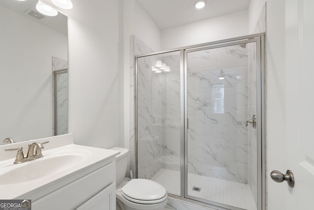 bathroom featuring a shower with shower door, vanity, and toilet