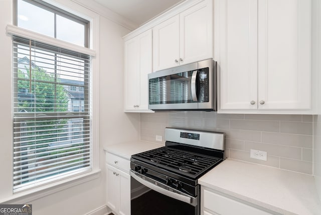 kitchen featuring decorative backsplash, white cabinetry, stainless steel appliances, and ornamental molding