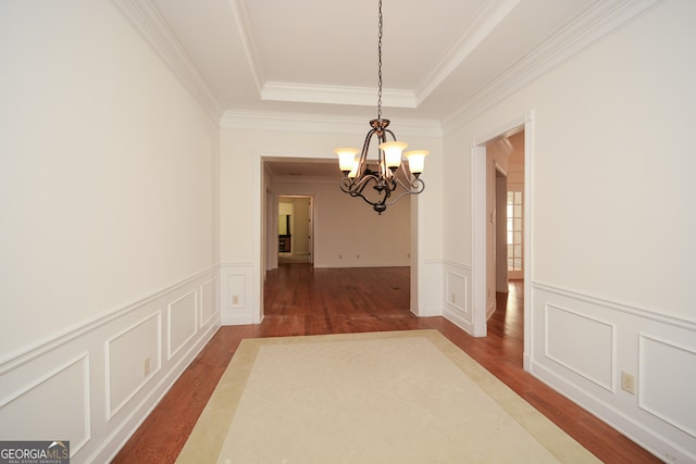 interior space with crown molding, a raised ceiling, dark hardwood / wood-style flooring, and an inviting chandelier