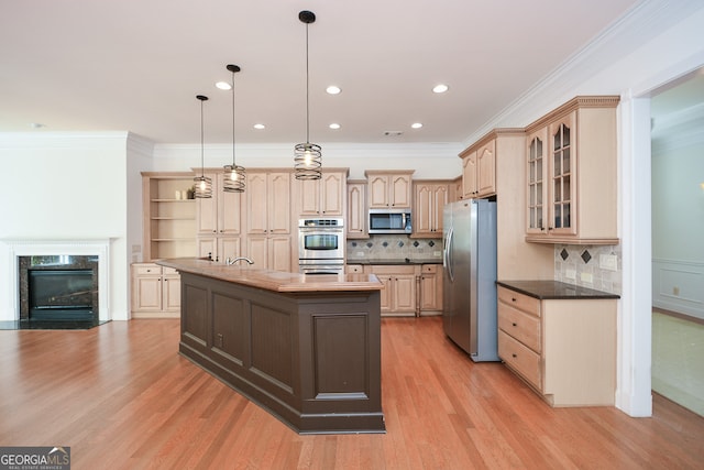 kitchen featuring light brown cabinetry, appliances with stainless steel finishes, a kitchen island, pendant lighting, and light hardwood / wood-style flooring