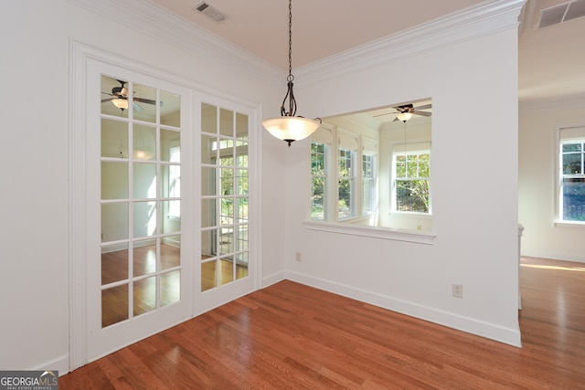 unfurnished dining area featuring ceiling fan, wood-type flooring, ornamental molding, and plenty of natural light