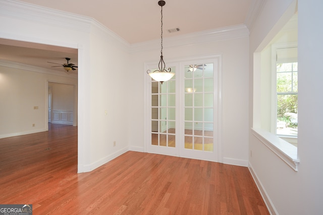 unfurnished dining area with hardwood / wood-style floors, crown molding, and ceiling fan