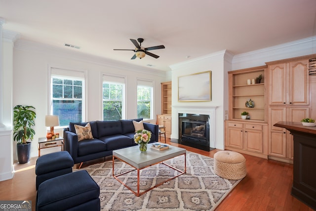 living room with ceiling fan, built in features, ornamental molding, and dark hardwood / wood-style floors