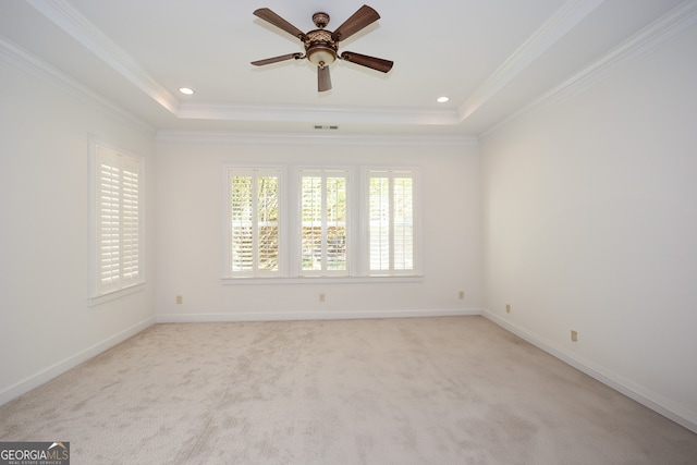 empty room with crown molding, ceiling fan, light colored carpet, and a raised ceiling