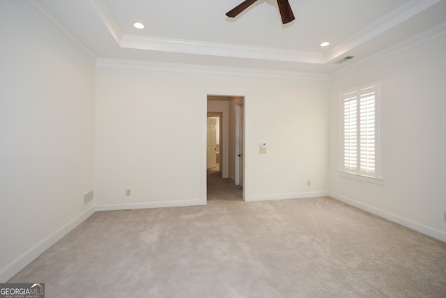 carpeted spare room with crown molding, a tray ceiling, and ceiling fan