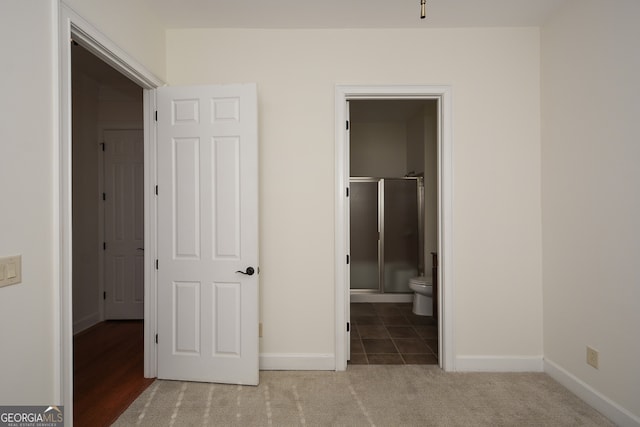 unfurnished bedroom with ensuite bath and light colored carpet