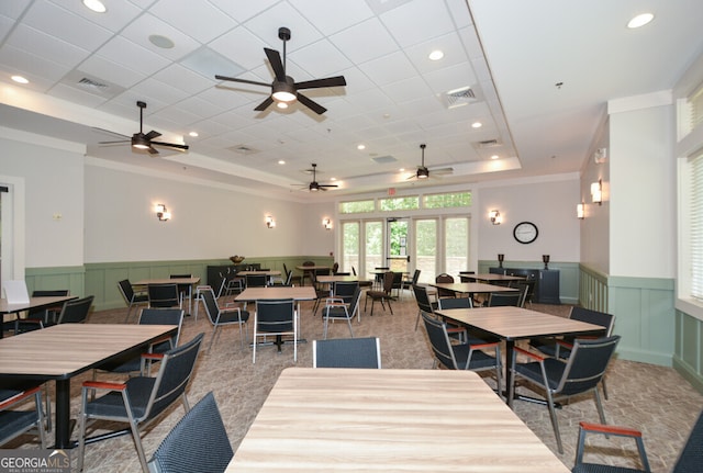 dining area featuring french doors, a raised ceiling, ornamental molding, and light colored carpet