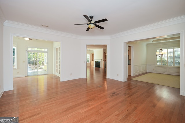 spare room with crown molding, wood-type flooring, and ceiling fan with notable chandelier