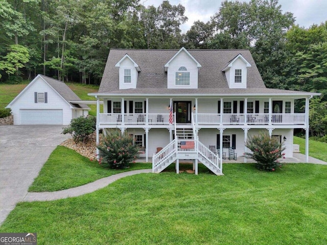 view of front of home featuring a garage, covered porch, a front yard, and an outdoor structure