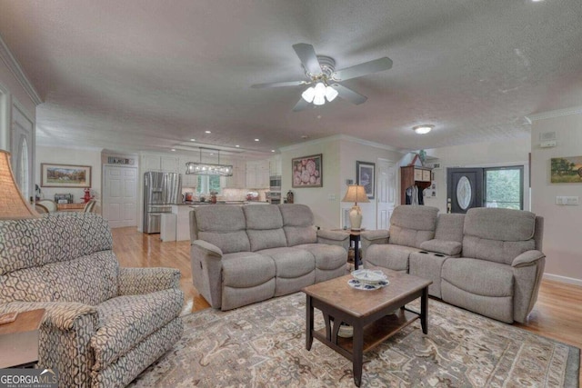 living room with light wood-type flooring, a textured ceiling, and crown molding