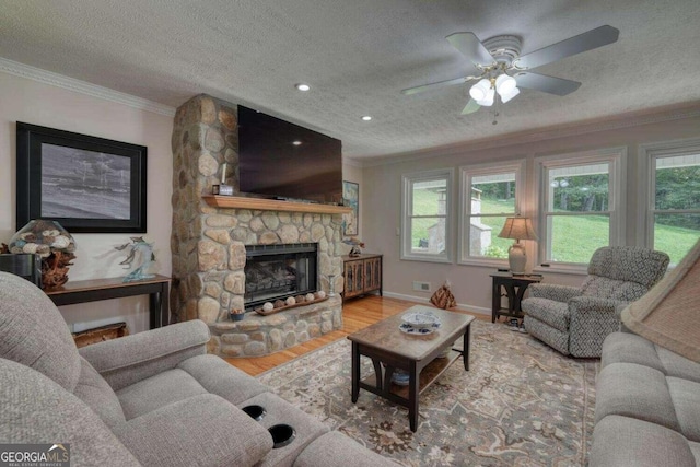 living room featuring a fireplace, a textured ceiling, ceiling fan, and light hardwood / wood-style flooring