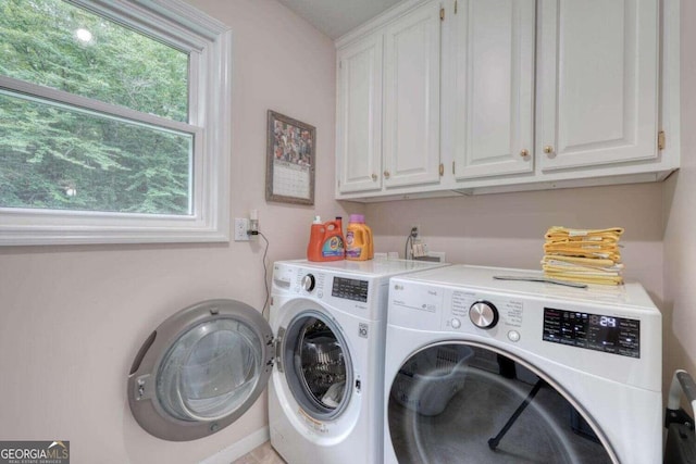 clothes washing area with cabinets and washer and dryer