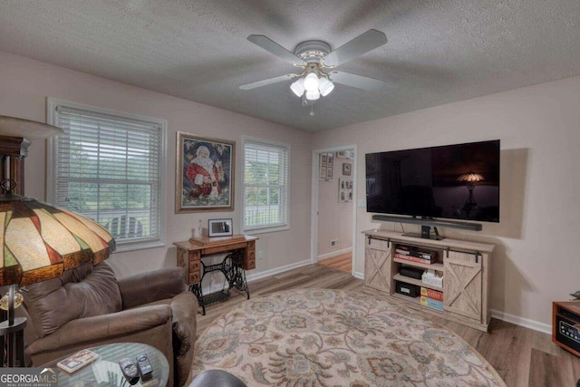 living room featuring light hardwood / wood-style floors, a textured ceiling, and ceiling fan