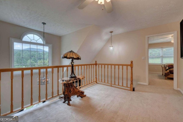 corridor featuring light colored carpet, a textured ceiling, and vaulted ceiling