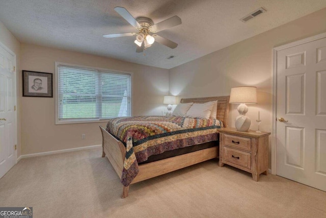 carpeted bedroom featuring ceiling fan and a textured ceiling