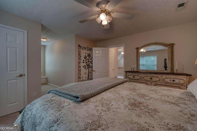 bedroom with a textured ceiling, light colored carpet, ceiling fan, and ensuite bathroom