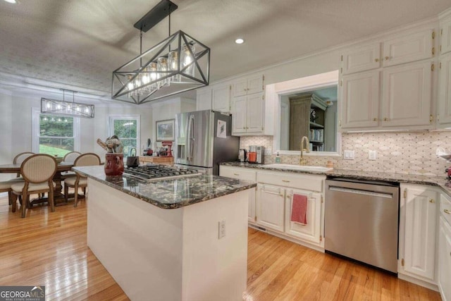 kitchen featuring stainless steel appliances, a center island, white cabinets, sink, and light wood-type flooring