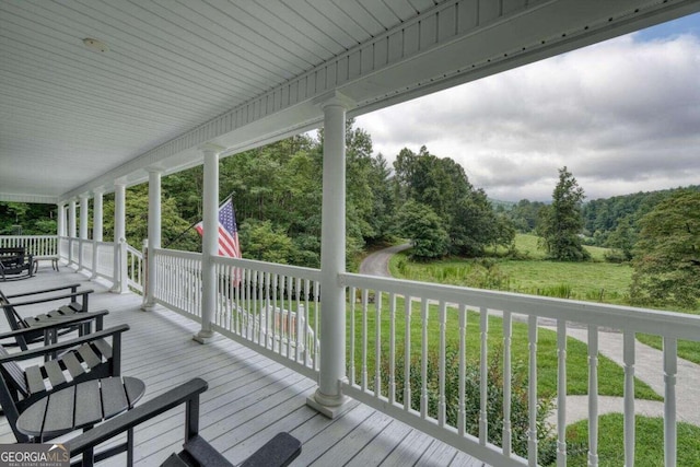 wooden deck with a lawn and a porch