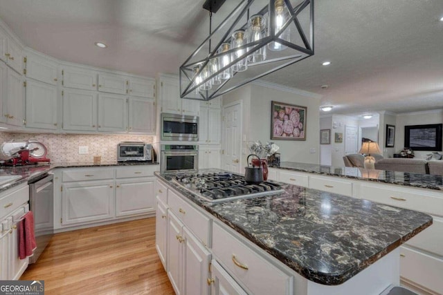 kitchen with crown molding, stainless steel appliances, white cabinetry, pendant lighting, and a center island