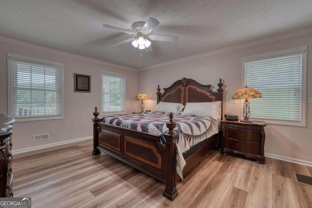 bedroom featuring ornamental molding, light wood-type flooring, a textured ceiling, and ceiling fan