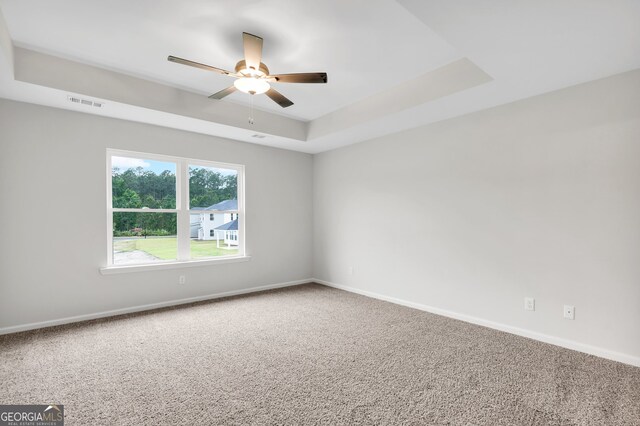 unfurnished room with carpet floors, a tray ceiling, and ceiling fan