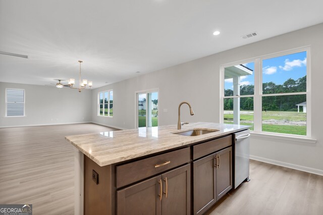 kitchen with a center island with sink, light stone counters, stainless steel dishwasher, light hardwood / wood-style flooring, and sink