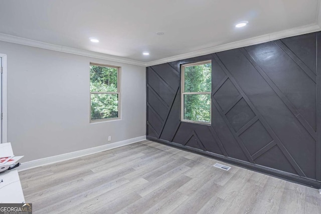 spare room with ornamental molding, light wood-type flooring, and plenty of natural light