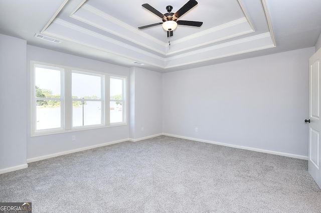 carpeted spare room featuring ceiling fan, ornamental molding, and a tray ceiling