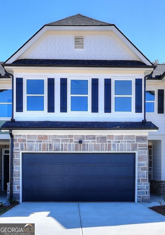 view of front of house with stone siding, driveway, and a garage